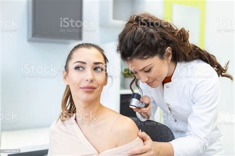 Dermatologist In Latex Gloves Holding Dermatoscope While Examining