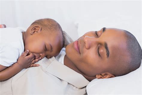 Happy Young Father Napping With Baby Son On Couch At Home In The Living