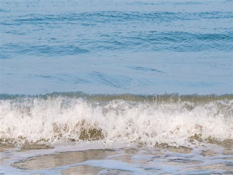 Small Breaking Waves On A Beach With Dark Brown Ocean Water Stock