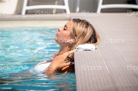 relaxed woman listening to the music with headphones bathing in a pool portrait happy girl