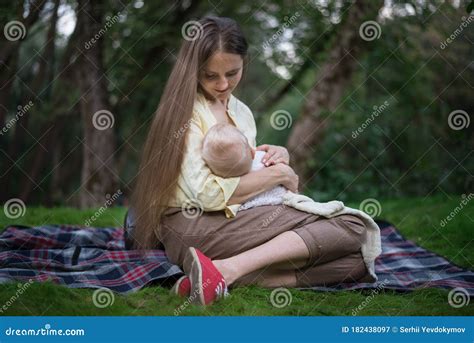 Mother Breastfeeds Her Baby Mom With A Newborn Sitting On Picnic