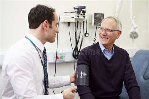 Doctor Taking Senior Patient S Blood Pressure In Hospital Stock Image