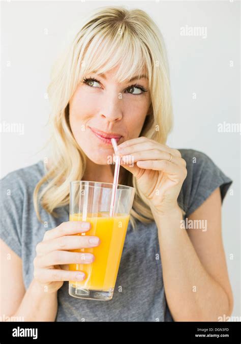 Studio Portrait Of Blonde Woman Drinking Orange Juice Stock Photo Alamy