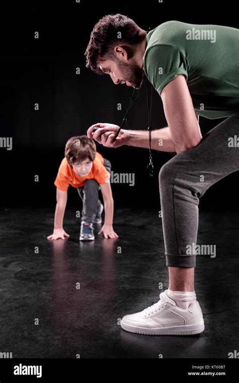 Man Controlling Time While Boy Training And Looking To Camera On Black