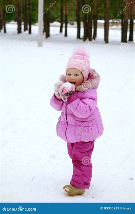 Маленькая девочка в розовой куртке играя с снегом Стоковое Изображение