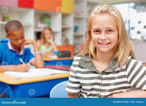 Shes Proud Of Her School And Education Confident Young Schoolgirl Sitting At Her Desk In Class