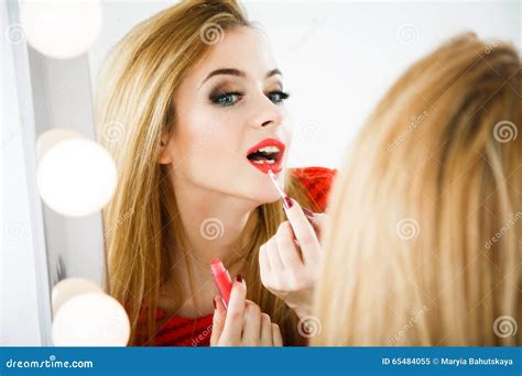 Mooie Vrouw Die Lippenstift Toepast Bij De Spiegel Stock Afbeelding