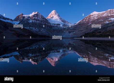 A Star Filled Sky Over Mount Assiniboine Reflected In Lake Magon Mount