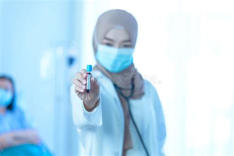 Young Muslim Female Doctor Holding Test Tube With Blood
