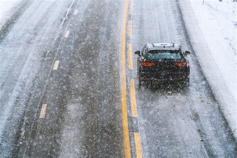 Car Driving On A Highway With Wet Slippery Asphalt During A Snow Storm