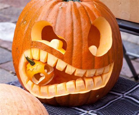 A Carved Pumpkin Sitting On Top Of A Table Next To Another Pumpkin With