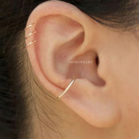 A Woman S Ear Is Shown With Two Small Gold Hoops On The Side