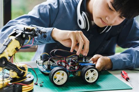 Asian Teenager Students Doing Robot Arm And Robotic Cars Homework