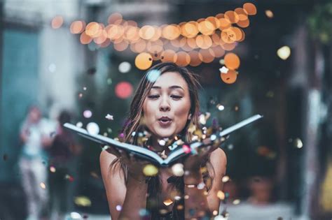 A Woman Is Reading A Book While Confetti Falls From Her Face And Hands