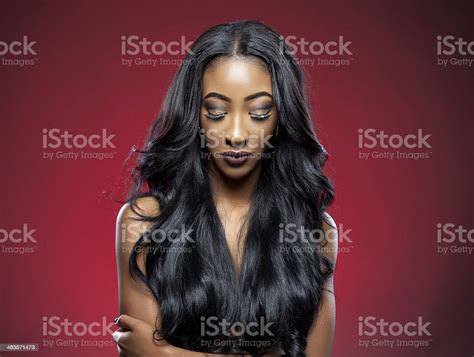 Young Woman With Long Black Wavy Hair Looking Down Stock Photo