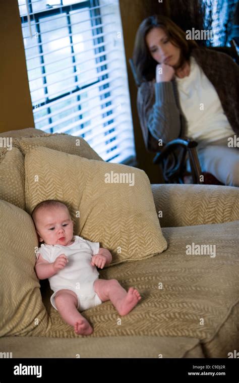 Mother Suffering From Postpartum Depression Sitting By A Window While