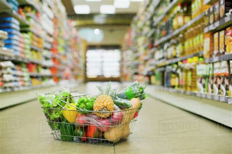 Close Up Of Full Shopping Basket On Floor Of Grocery Store Stock