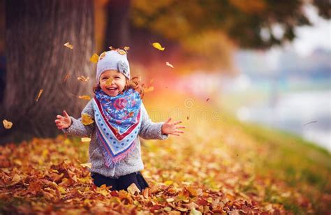 Adorable Happy Girl Throwing The Fallen Leaves Up Playing In The