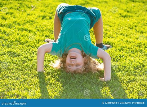 Happy Kid Boy Girl Standing Upside Down On Her Head On Grass In Summer