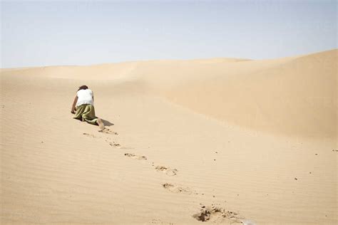 Man Crawling On All Fours Alone In The Desert Stock Photo