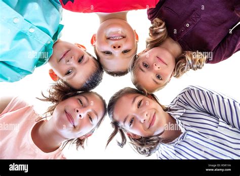 Group Of Children Of Various Ages Standing In Circle Looking Down Into