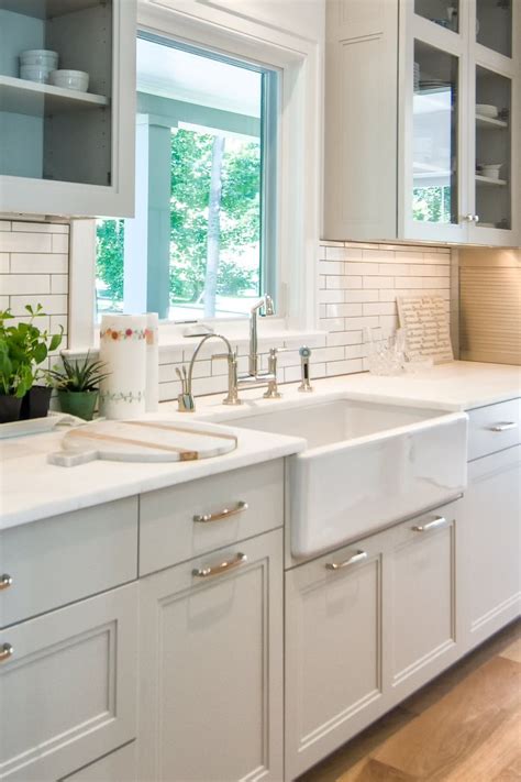 white shaker cabinets subway tiles backsplash quartz countertops light wood floor farmhouse sink