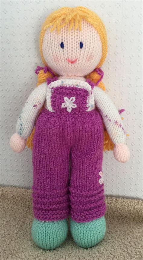 A Knitted Doll With Blonde Hair Wearing Purple Pants And Pink Shoes