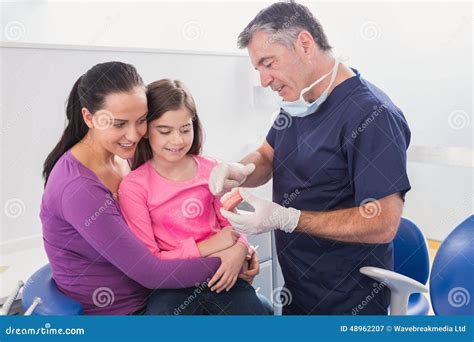 Pediatric Dentist Explaining To Young Patient And Her Mother The Model