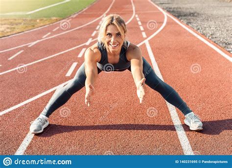 Sporty Lifestyle Young Woman On Stadium Legs Aside Stretching On Track