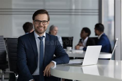 Handsome Businessman Sit At Desk With Laptop Staring At Camera Stock
