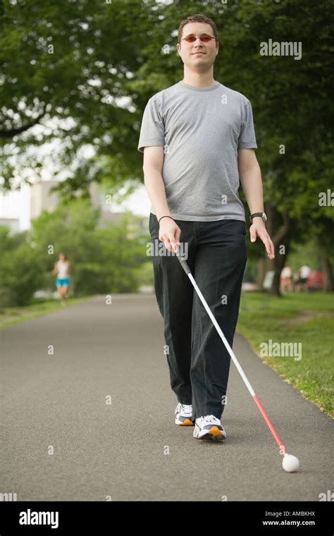 Blind Man Walking On A Walkway With A Blind Persons Cane Stock Photo
