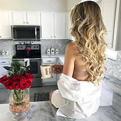 A Woman Sitting On The Kitchen Counter With Roses In A Vase Next To Her