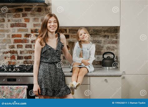 A Young Smiling Mother Is Posing With Her Happy Daughter In The Kitchen Stock Image Image Of