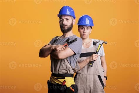 confident professional renovators posing with pair of pliers and hammer holding slegdehammer