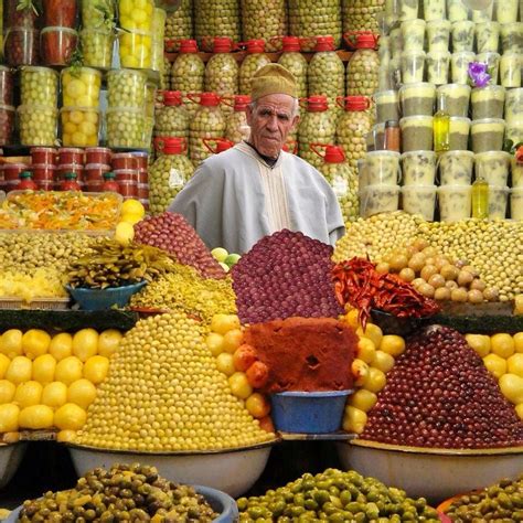 A Man Standing In Front Of A Display Of Fruits And Vegetables