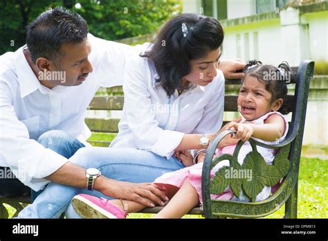 Indian family outdoor. Parents is comforting their crying daughter