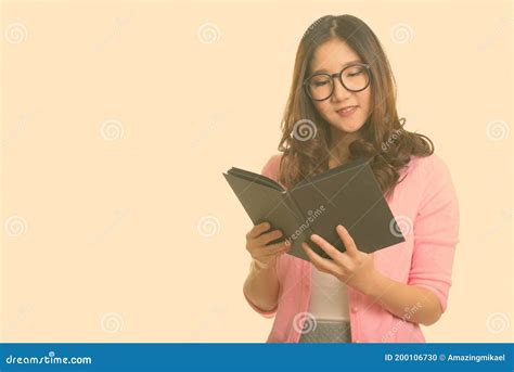 Portrait Of Happy Young Beautiful Asian Nerd Woman Reading Book With