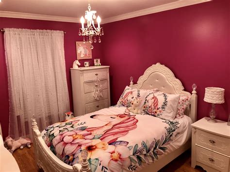 A Bedroom Decorated In Pink And White With Flowers On The Bedspread