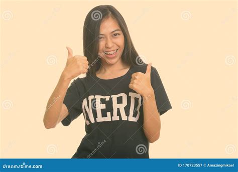 Studio Shot Of Young Happy Asian Teenage Nerd Girl Smiling And Giving