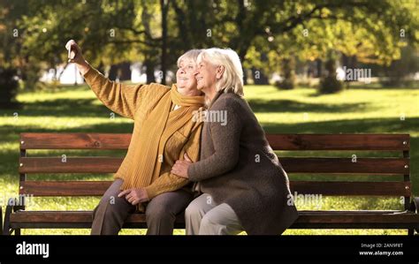 Deux Vieilles Femmes Prenant Le Téléphone Mobile Sur Selfies Assis Sur Un Banc De Parc