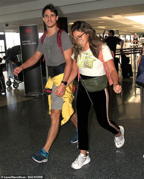 gina rodriguez smiles as she walks hand in hand with her husband joe locicero at the airport