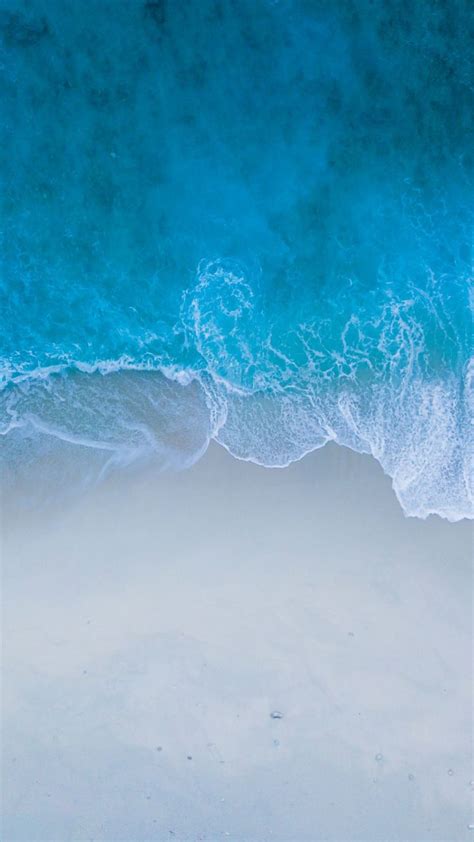 An Aerial View Of The Ocean And Beach With Waves Crashing In To Shore