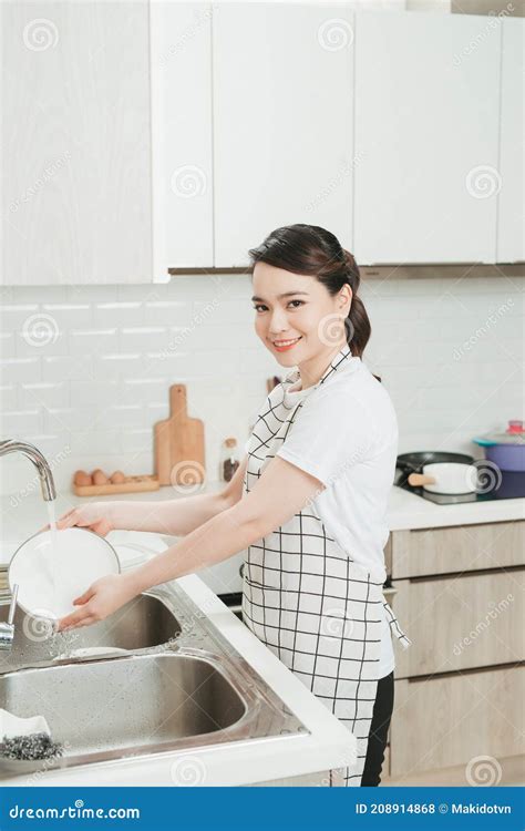 Beautiful Smiling Young Woman Washing The Dishes In Modern White