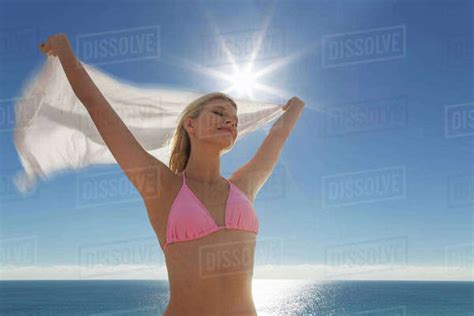 Caucasian Woman In Bikini Holding Fabric At Beach Stock Photo Dissolve