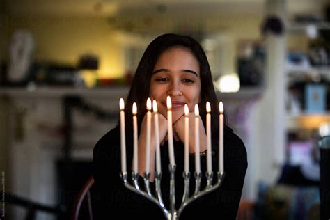 hanukkah teen girl gazes at menorah and candles by stocksy contributor sean locke stocksy