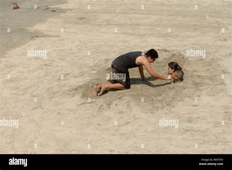 Young Couple Buried In The Sand Up To Their Necks By Another Friend