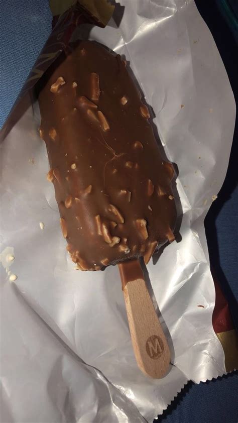 An Ice Cream With Nuts On Top Sits In A Wrapper
