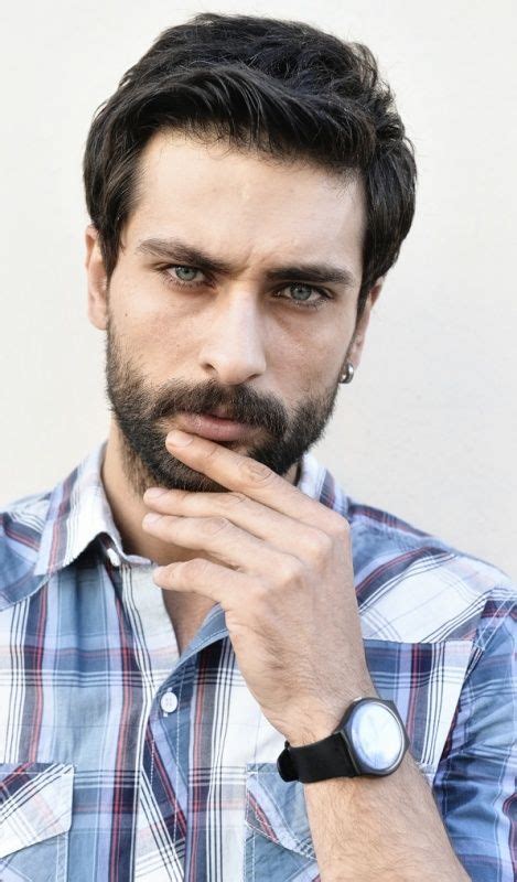 a close up of a person with a watch on his wrist and wearing a plaid shirt