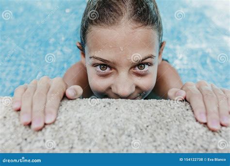 Beautiful Teenager Girl Floating In A Pool And Looking At The Camera