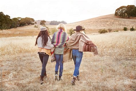 Three Women Friends Walking In Open Field In Nature By Stocksy Contributor Trinette Reed